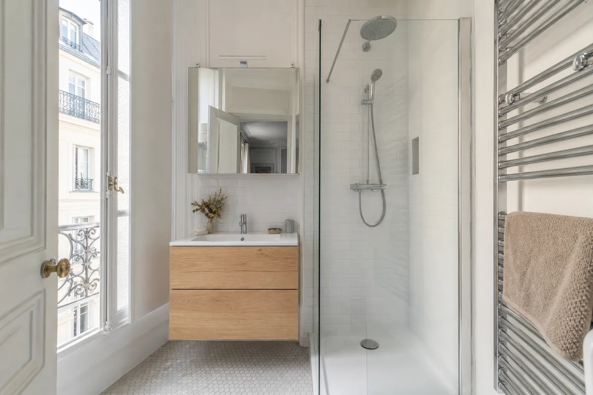 Salle de bain rénovée avec douche à l’italienne et faïence claire dans un appartement haussmannien