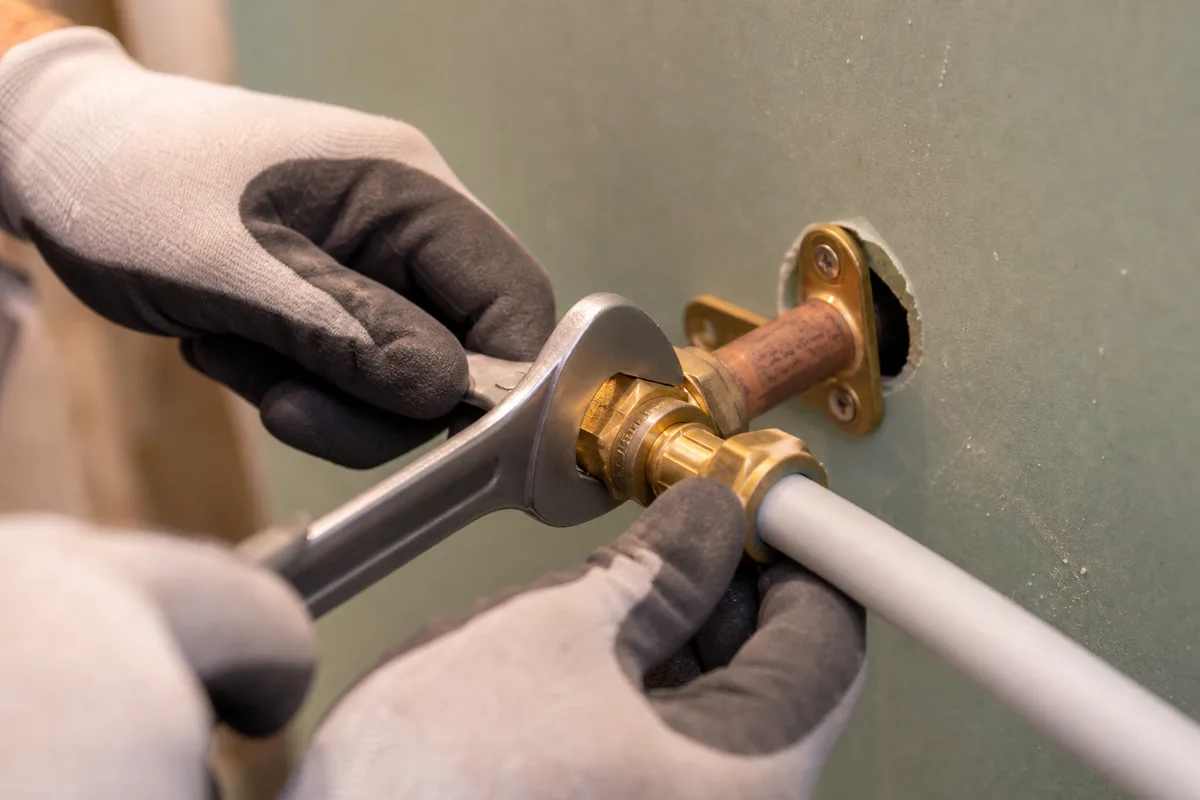 Plombier raccordant les arrivées d&rsquo;eau d&rsquo;une salle de bain en cours de rénovation